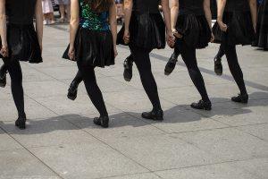 Irish dancing girls in courtyard wearing black and green costume and wearing heavy shoes