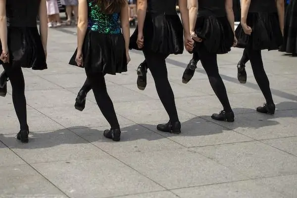 Irish dancing girls in courtyard wearing black and green costume and wearing heavy shoes