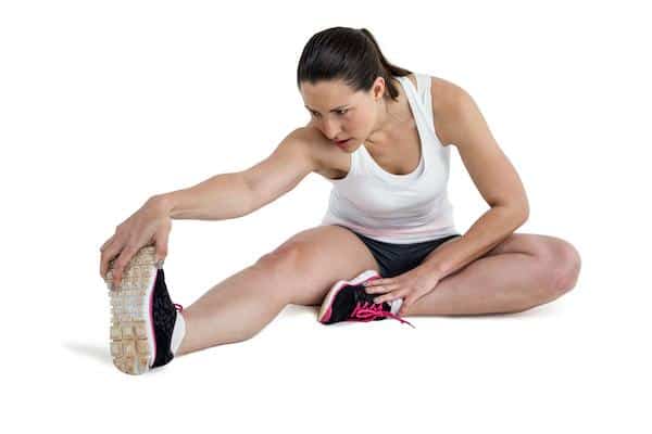 A woman doing a hamstring stretching exercise on a white background.