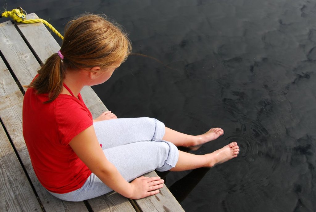 Girl sitting with her feet in the water, reflecting on the experience of her first Irish dance Feis